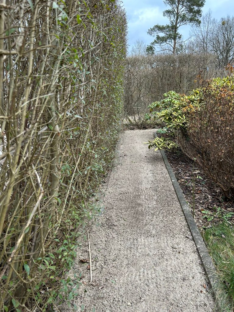 Aufgeschütteter Weg entlang der zur Straße liegenden Hecke