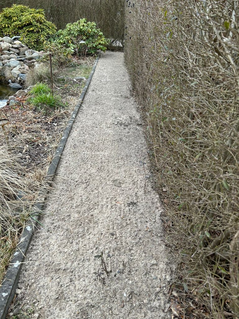 Aufgeschütteter Weg entlang zur Auffahrt verlaufenden Hecke