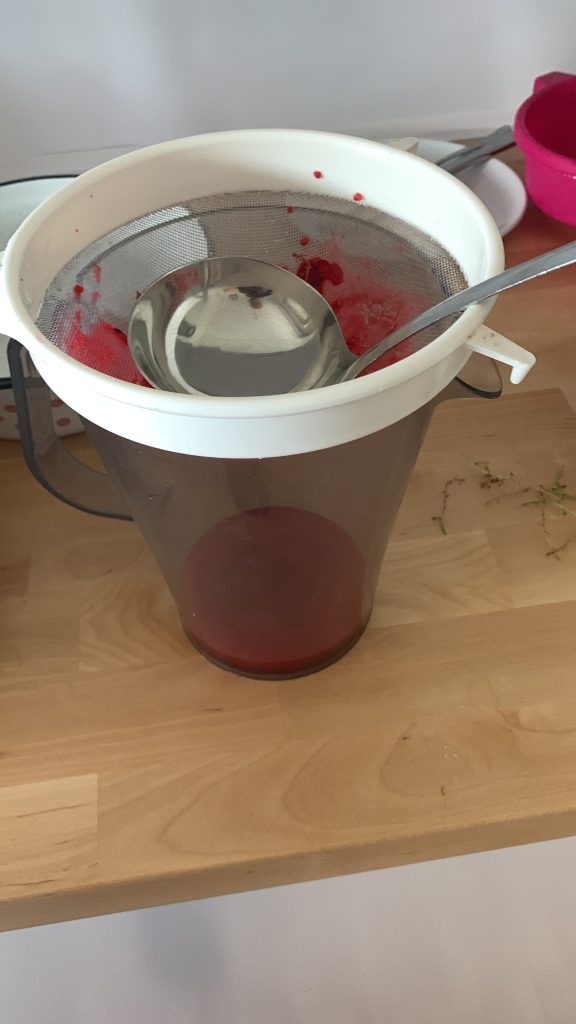 Ausquetschen der Beeren mit Sieb und Kelle