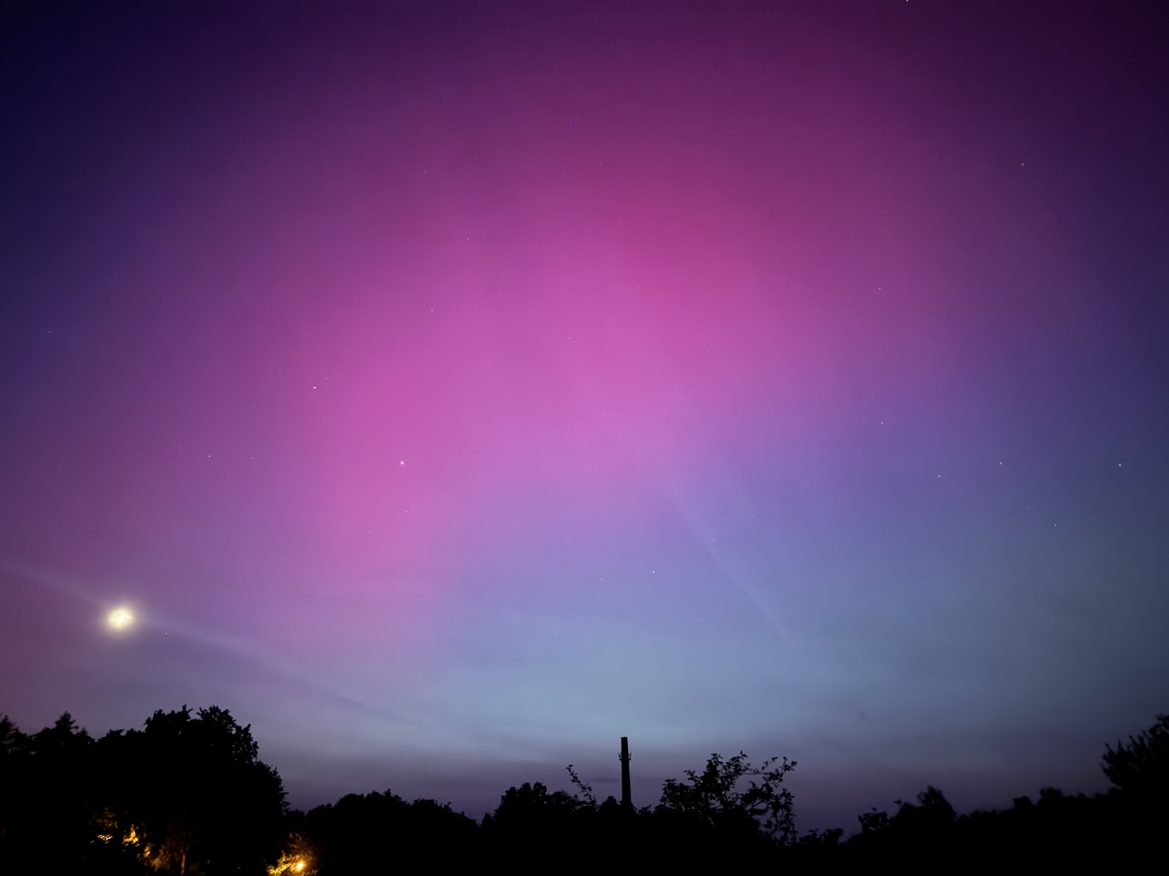 Links der Mond, mittig im Bild das Polarlicht.